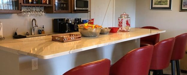 A kitchen with a bar and red chairs.